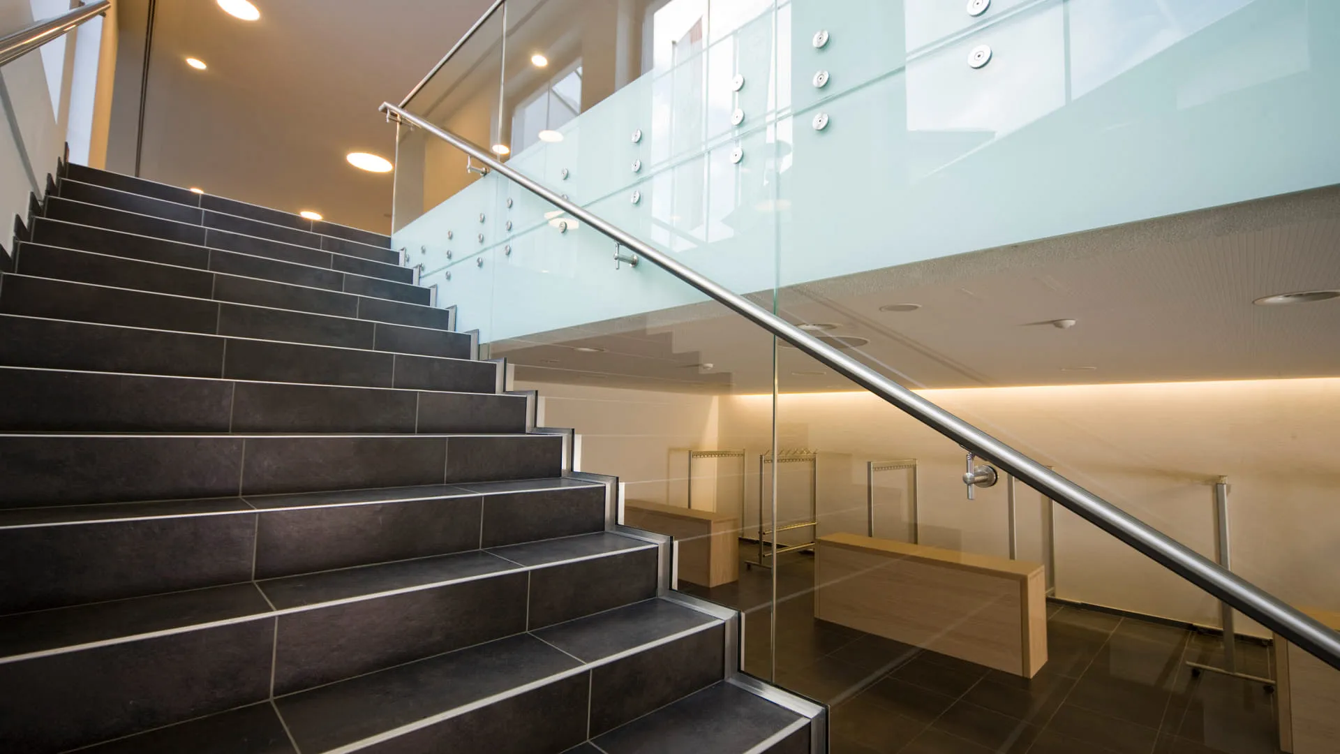 Moderne Treppe mit Glasgeländer und Holzregalen