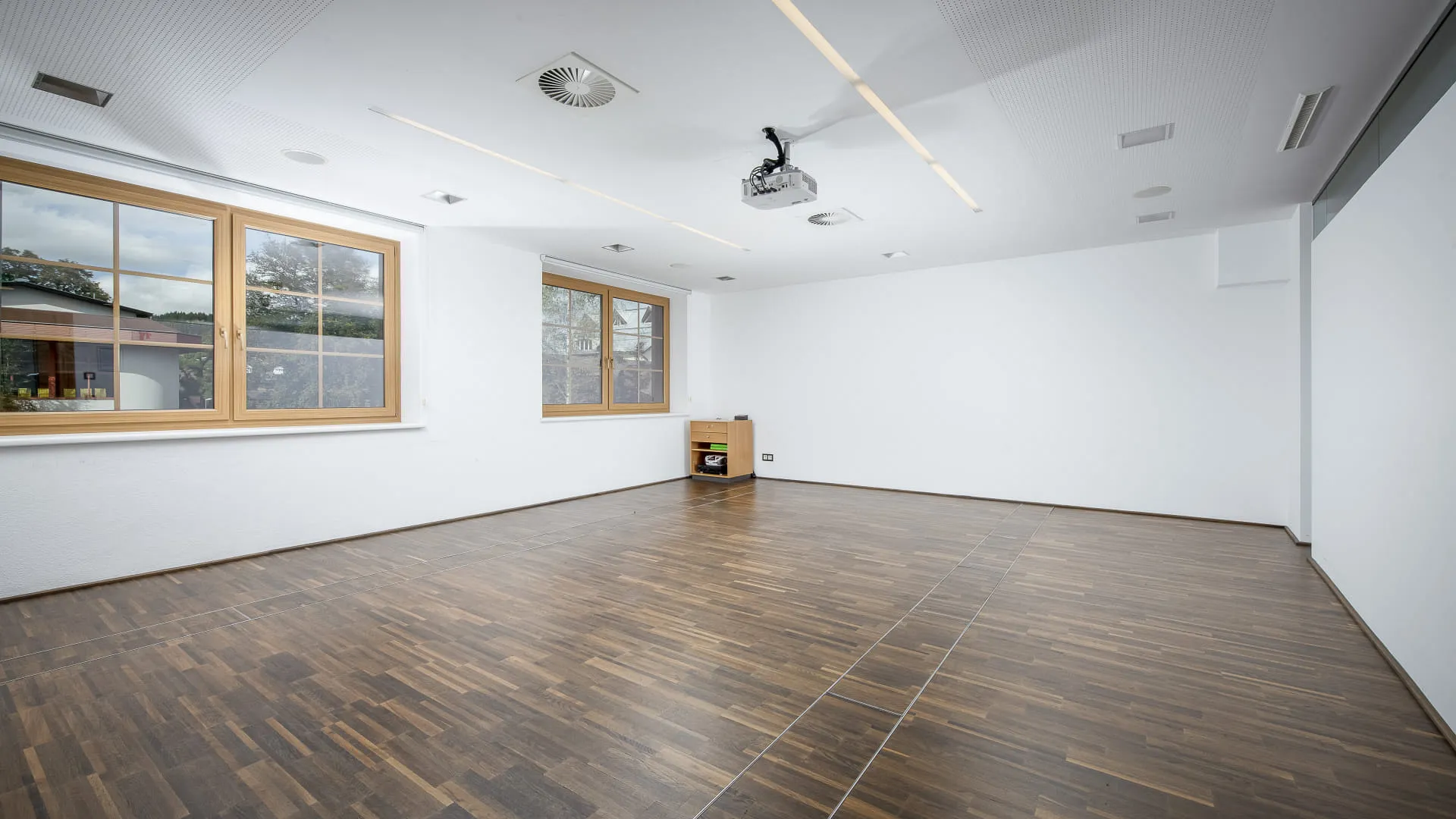leerer Raum mit Holzboden und großen Fenstern