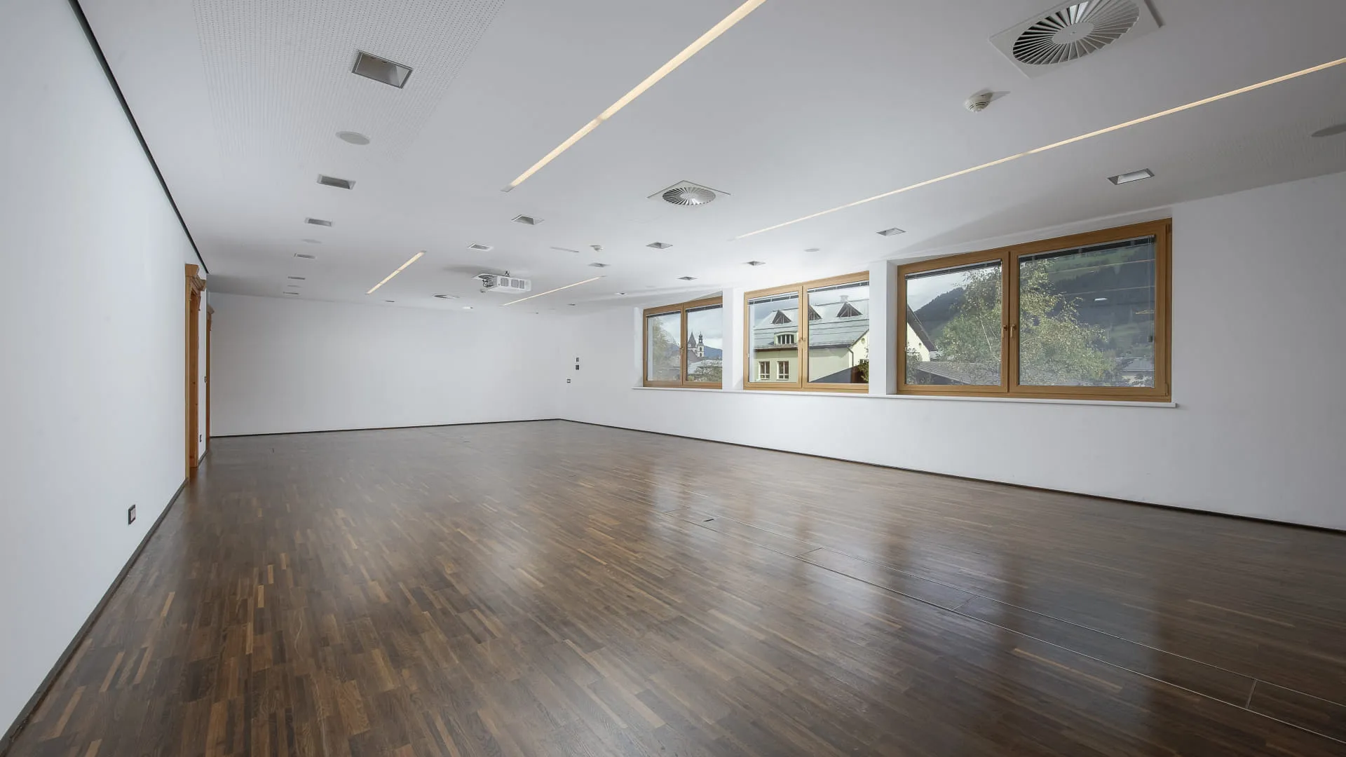 Heller, leerer Raum mit Holzfußboden und Fenstern
