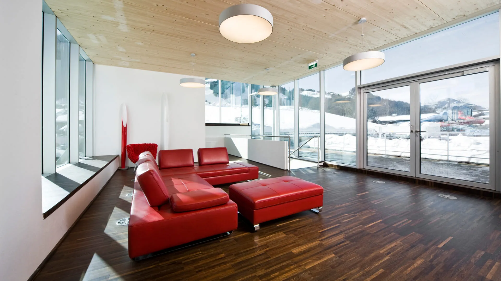 Moderne Wohnung mit roten Sofas und großen Fenstern.